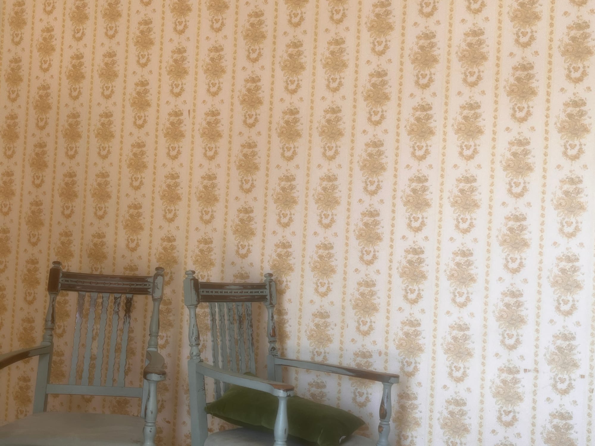 two chairs against a backdrop of old timey wallpaper